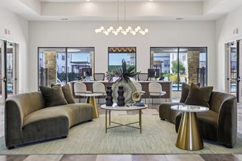 A modern living room with a large grey sofa, a round gold table, and a chandelier.